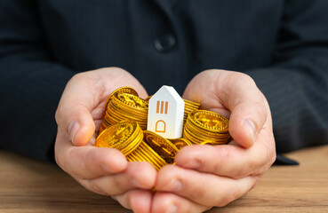 House on a handful of cash coins in hands. Housing prices. Save up to buy a house. Take out a mortgage. The cost of real estate or the land underneath it. Land value