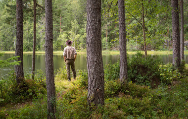 Man looking over a small lake in a forest