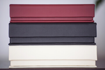 stack of photoook boxes. Wedding boxes of photobook in brown fabric and white, red and black leather binding. Wedding photo box, album family.  cover of genuine leather. Services of a typography 