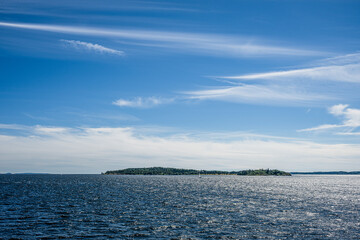 scenic view of a distant island under a vast blue sky with wispy clouds.