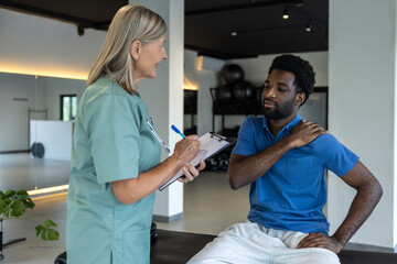 Female physical therapist talking to male patient and making notes