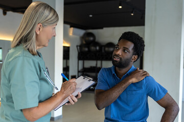 Female physical therapist talking to male patient and making notes