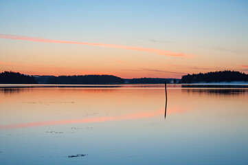 Early summer night by a calm lake in Finland with fog rising from the water