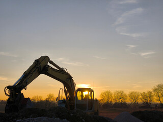 Excavator in front of the sunset on the horizon