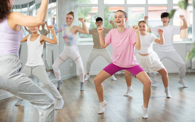 Naklejka premium Female girl student repeats movements of unrecognizable teacher during group modern dance class. Hobbies, active pastime, additional extracurricular activities for children and teenagers