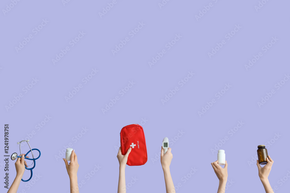 Poster Female hands with first aid kit, stethoscope, pills and thermometer on lilac background