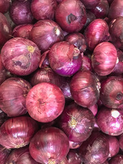 Close-up of fresh red onions with vibrant tones and shiny texture. Perfect for markets, recipes, and culinary content.