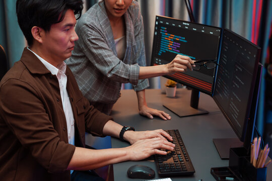 IT developers discussing with point to intelligent website development coder system running data online two screens information technology at neon light room at modern office. Infobahn.