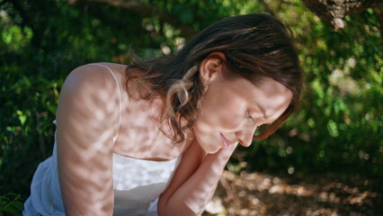 Thoughtful girl resting nature forest reflecting sun shadows on face closeup