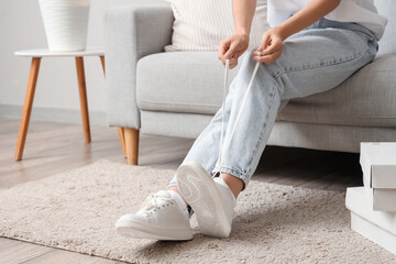 Woman in white sneakers sitting on sofa at home