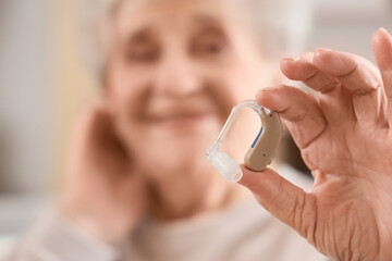 Fototapeta premium Senior woman with hearing aid at home, closeup