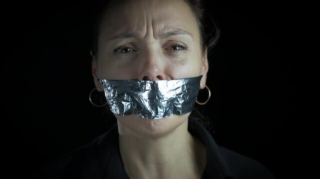 Female with tape on mouth to shout. A view of female with closed mouth stand with tape because of violence problems.