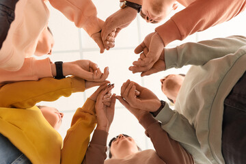 Group of people holding hands together indoors, bottom view