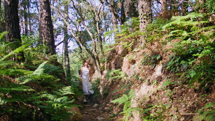 Dreamy girl strolling jungles alley with lush greenery. Carefree woman walking