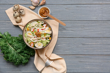 Bowl of salad with crab sticks, iceberg leaves, corn, quail eggs and cucumber on grey wooden background © Pixel-Shot