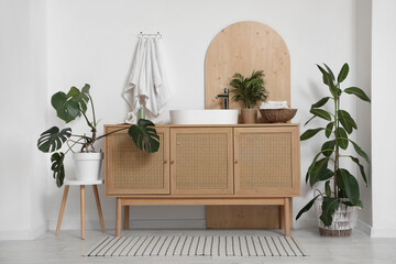 Houseplants and hanging clean towels on white wall near modern sink in bathroom