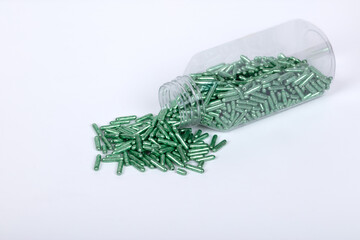 Fototapeta premium Transparent Plastic Bottle with Green Spherical Pills on White Background – Medicine, Healthcare, and Pharmaceutical Supplement Concept