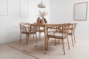 Vases with dried flowers on dining table in light room interior