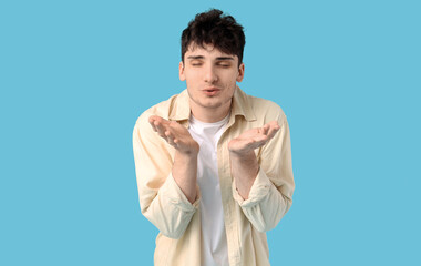 Handsome young man blowing kiss on blue background