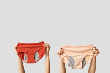 Female hands with different period panties on grey background