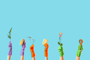 Many female hands in rubber gloves with sponges and flowers on blue background