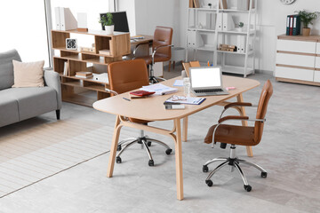 Interior of light office with desk and shelf units