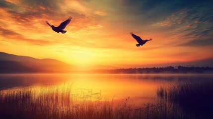 Obraz premium An enchanting image of two doves soaring high above a tranquil lake at sunset, their silhouettes contrasting against the warm colors of the evening sky