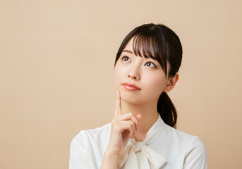 目線を上に向けて考え事をする女性