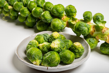Obraz premium Green brussels sprouts on stalk on white table