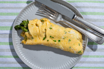 Chicken eggs omelette stuffed with green asparagus, tasty vegetarian food, french cuisine, close up