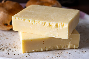 Block of aged cheddar cheese, the most popular type of cheese in United Kingdom and USA, natural cheese from cow milk