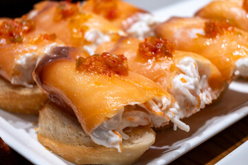 Typical snacks of Basque Country, pinchos or pinxtos skewers with small pieces of bread, fish, sea food, sweet green pepper served in bar in San-Sebastian or Bilbao, Spain