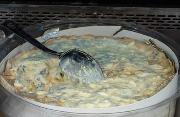Italian food, buttery or firm blue cheese made from cow milk in Gorgonzola, Milan, Italy in large box on Italian farmers market