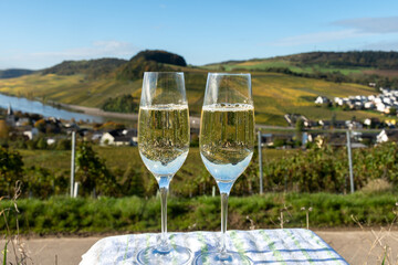 Tasting sparkling white wine, traditional champagne method making of cremant in caves on Moselle river valley in Luxembourg, glasses of wine and view on terraced vineyards