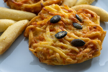 Pumpkin grated roasted patties, rosti or latkes and Fingernudel, finger potato noodle, dumplings decorated with pumpkin seeds