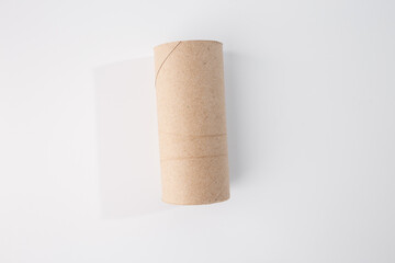 Empty cardboard toilet paper roll on white background. Cylindrical shape, brown cardboard, no markings. Common household item for DIY projects or crafts after use. Ideal for creative craft ideas