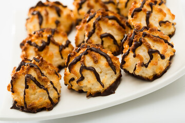 Gentle baked coconut dessert with chocolate topping served on white plate..