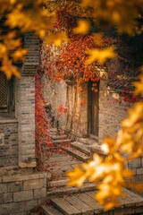Vibrant autumn leaves frame a rustic pathway leading to an inviting door in a quaint village