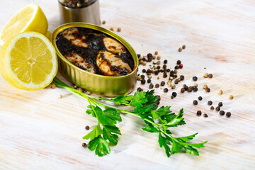 Seafood appetizer. Marinated calamari chipirones in squid ink in open tin can on wooden table with greens and lemon