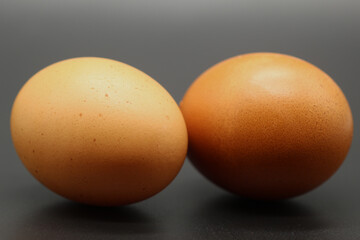 Two large brown eggs isolated on a dark background