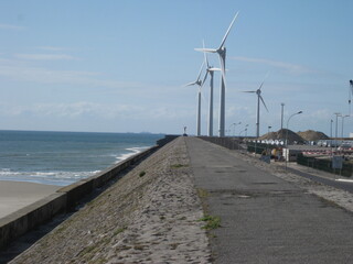 Wind turbine along a concrete jetty by the sea - Éolienne le long d'une jetée en béton au bord de la mer
