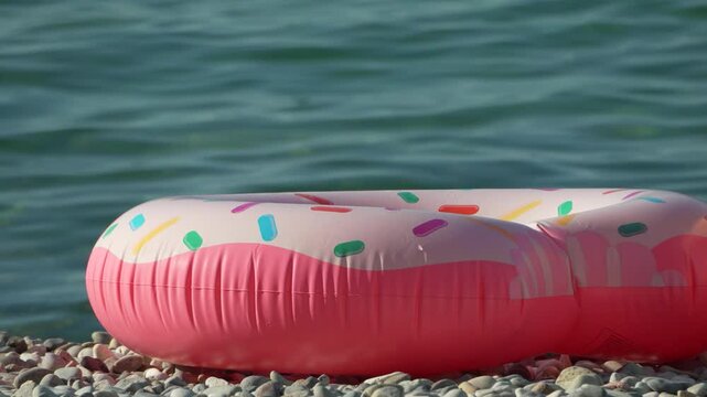 Pink Donut Pool Float on a Pebble Beach