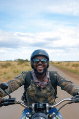 Fototapeta premium Happy motorcyclist wearing a helmet and sunglasses, riding along a scenic country road during a solo trip, embracing the thrill of freedom and adventure in the great outdoors