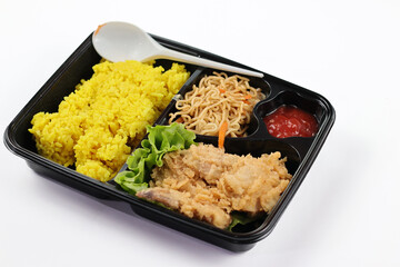 Nasi kuning or yellow rice in a bento box isolated on white background. Yellow Rice is an Indonesian fragrant rice dish cooked with coconut milk and turmeric.
