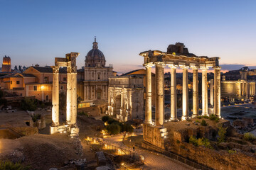 Naklejka premium Dusk at the Roman Forum and archaeological zone encompassing the ancient site lit up with lights. Rome, Italy