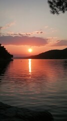 Fototapeta premium Sunset over calm water, reflecting the fiery sky. Peaceful evening scene.
