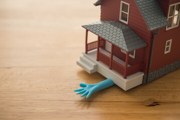 House crushes human hand on wooden table with copy space. Mortgage loan or high interest rate debt, home finance, finance and economy in crisis, FED increase interest rate effect, bankruptcy concept.