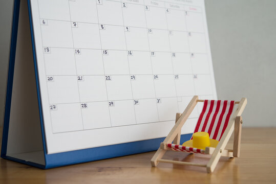 Red beach chair, hat and white blank calendar. Annual leave travel period for relaxation concept. Period of paid time off (PTO) granted to employees by their employer.