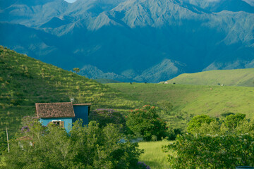 Blue house surrounded by lush green hills and mountains, Cruzeiro, Brazil