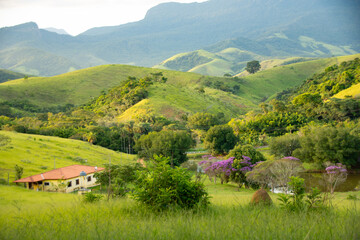 Rolling green hills with farmhouse in lush valley, Cruzeiro, Brazil